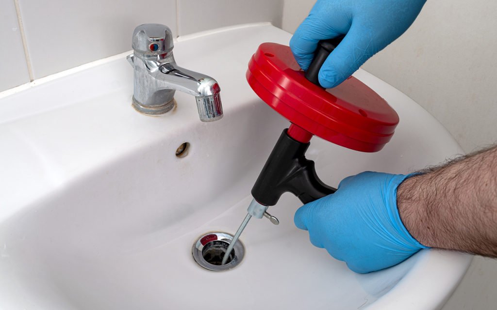 Person using auger in a sink drain